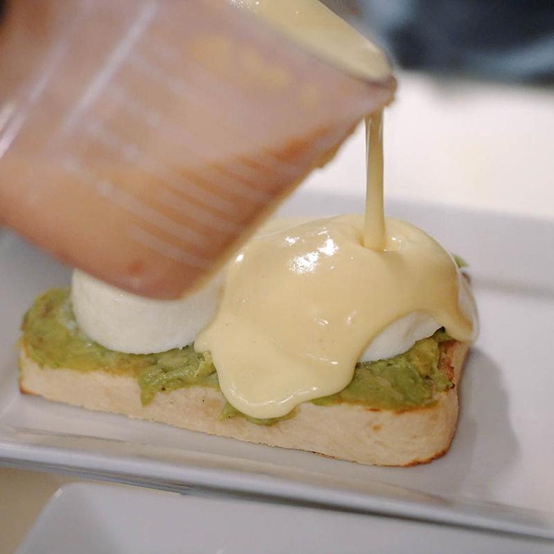 Avocado bennies sandwich being prepared.